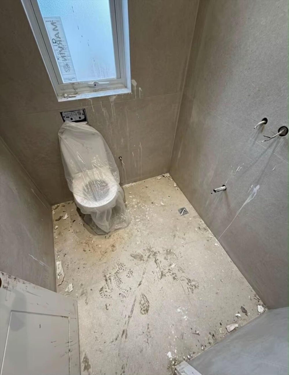 חדר שירותים עם אבק בנייה, כתמי צבע ורצפה מלוכלכת לפני הניקיון